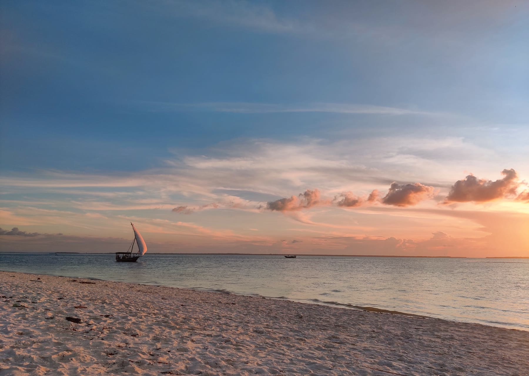 Traditional dhow sailboat on the beach at sunset
