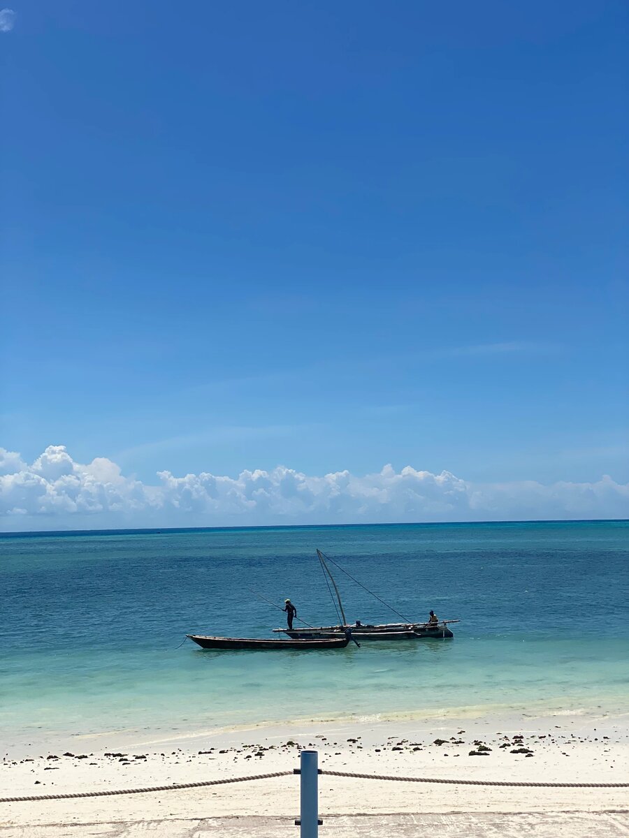 Fishermen on turquoise water off a white-sand Zanzibar beach